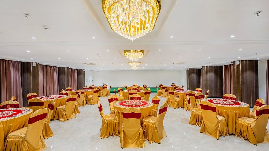 Lemonridge Hotels, KPHB | Banquet hall with round dining tables and chairs, featuring a unique ceiling light.